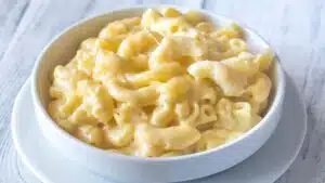 Wide closeup on the cooked macaroni and cheese without flour in a white bowl on light background.