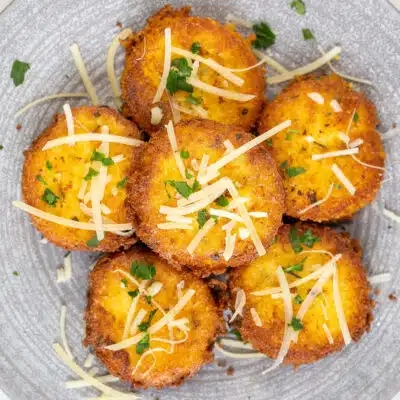 Best polenta cakes served on grey plate with grated parmesan cheese and fresh herbs.