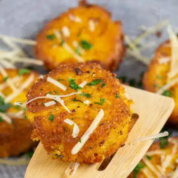 Golden, delicious polenta cakes being served on wooden spatula.