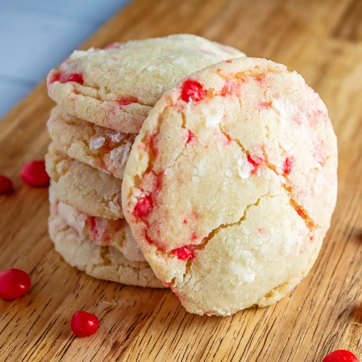 Tender biscoitos quentes vermelhos empilhados na bandeja de madeira com doces quentes vermelhos espalhados ao redor.