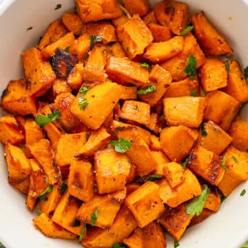 Wide overhead of the bowl of sauteed sweet potatoes with fresh chopped parsley.