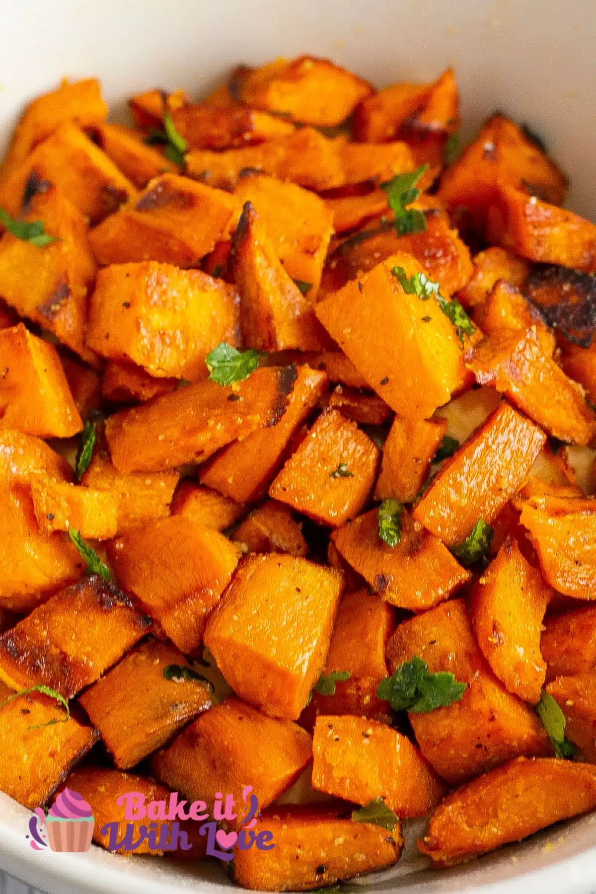 Sauteed sweet potatoes served in a white bowl with fresh chopped parsley.