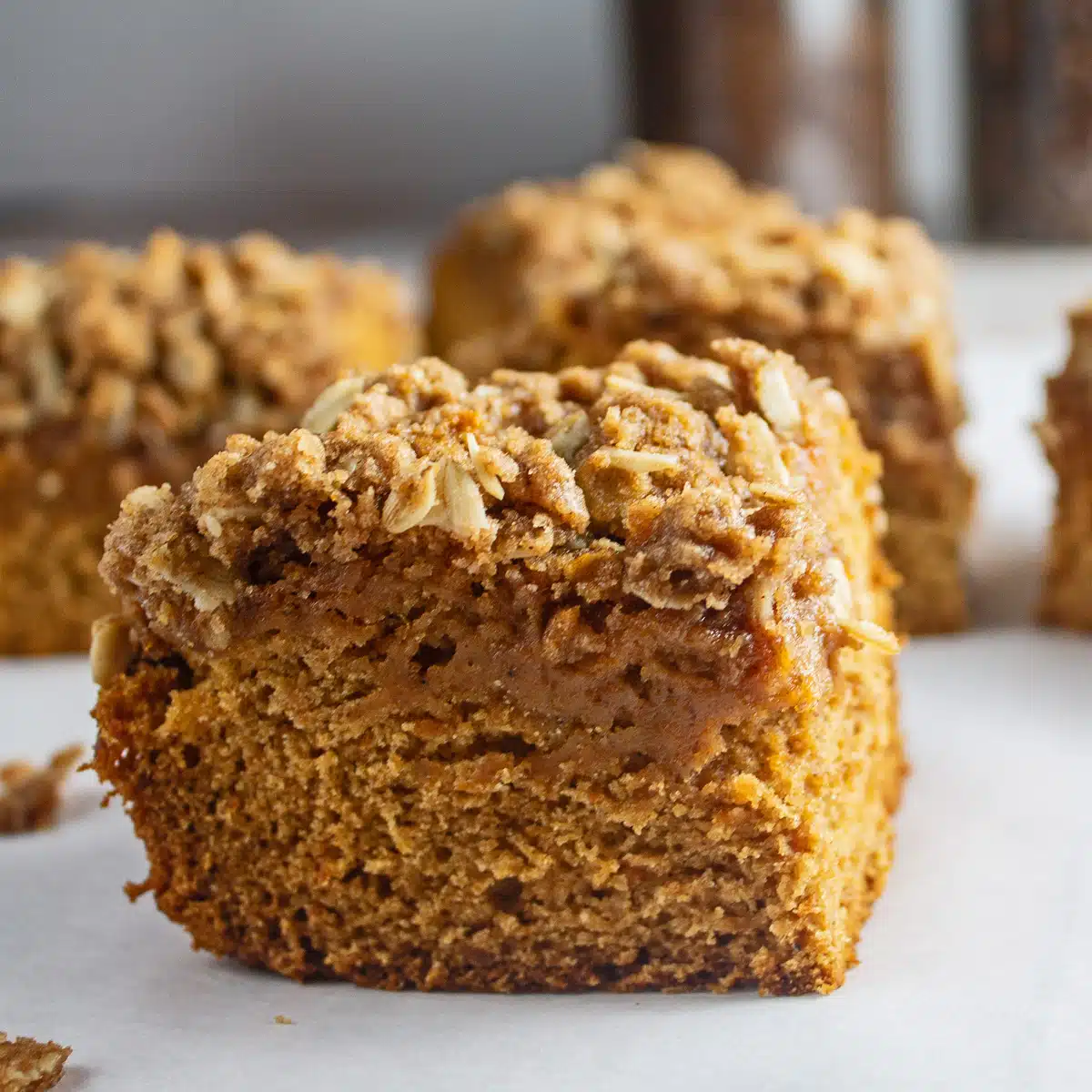 Square slice of sweet potato coffee cake on a light background with several other squares nearby.