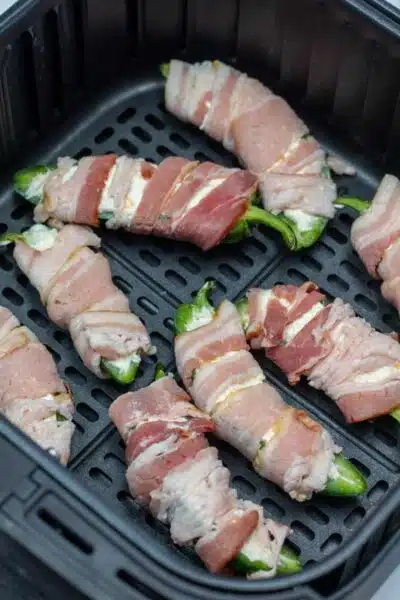 Process image 7 showing filled jalapenos wrapped in bacon in air fryer.