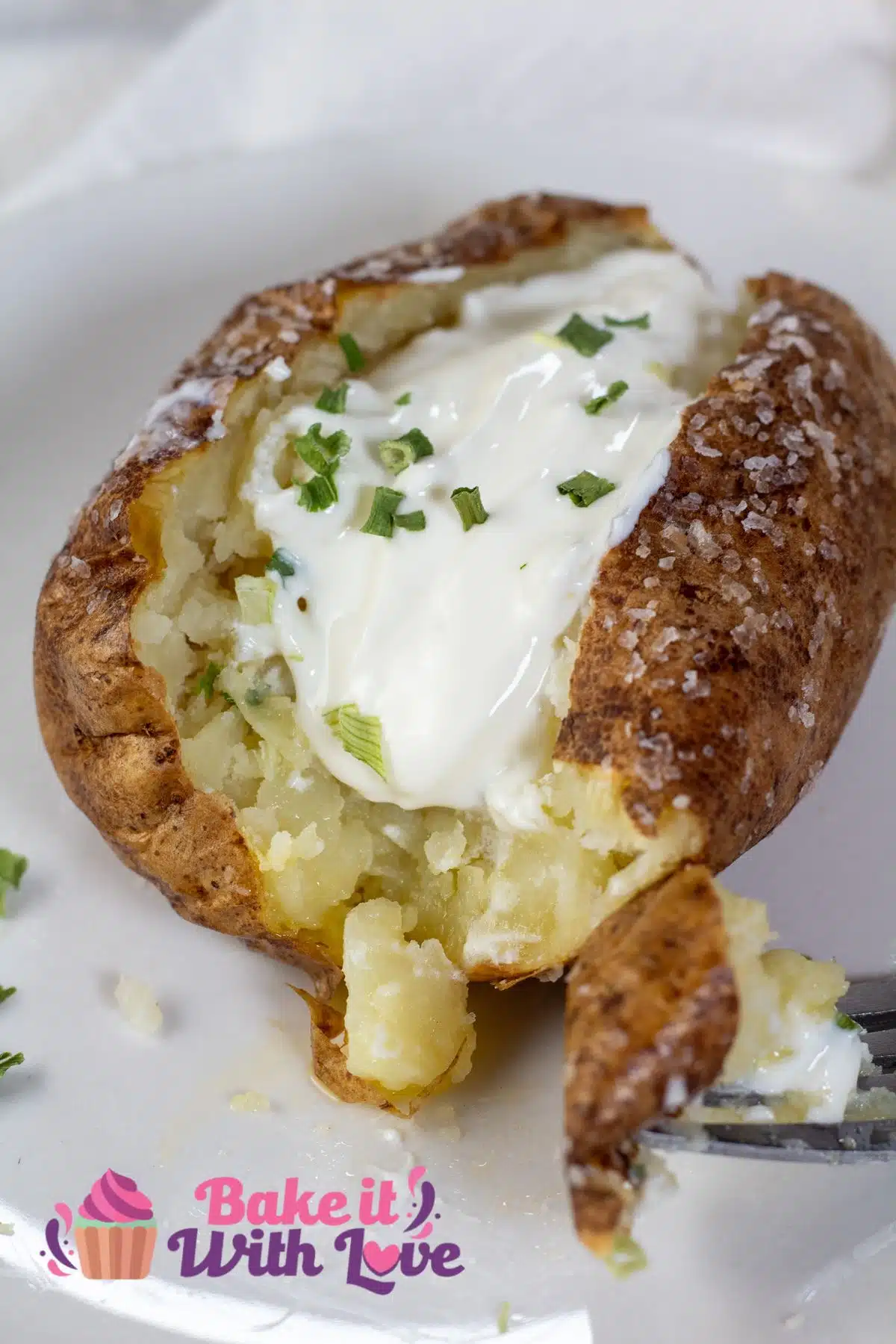Tall image of air fryer baked potato with sour cream and chives.