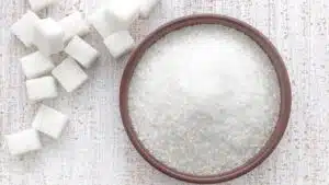 Wide image of a bowl of sugar and sugar cubes.