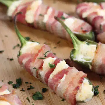 Wide image of bacon wrapped jalapeno poppers with cream cheese.