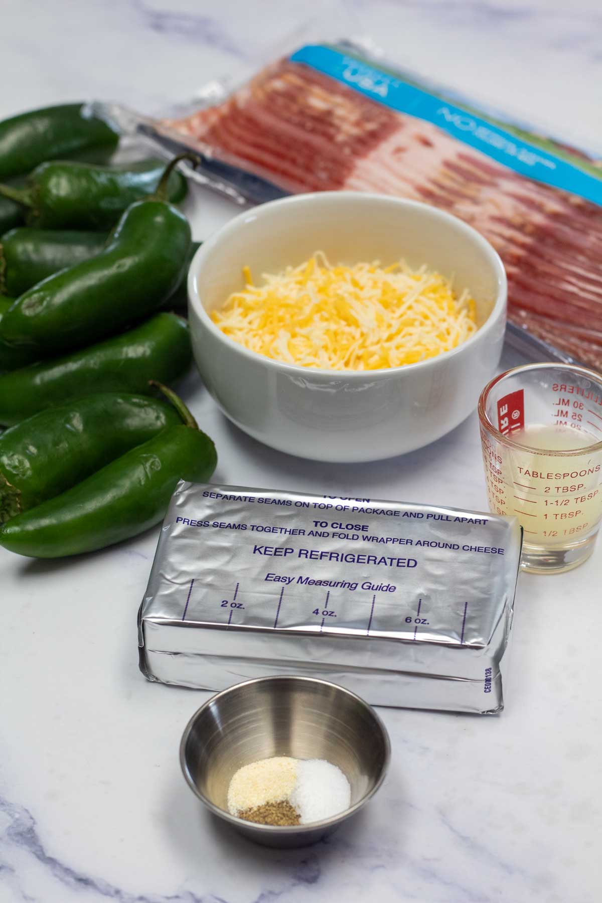 Tall image showing ingredients needed for bacon wrapped jalapeno poppers with cream cheese.