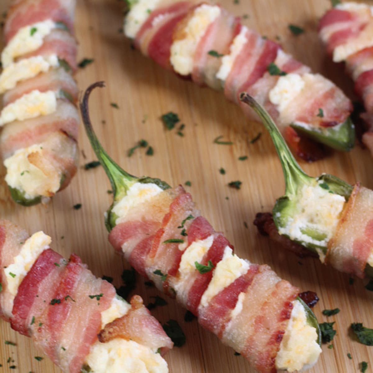Square image of bacon wrapped jalapeno poppers with cream cheese.