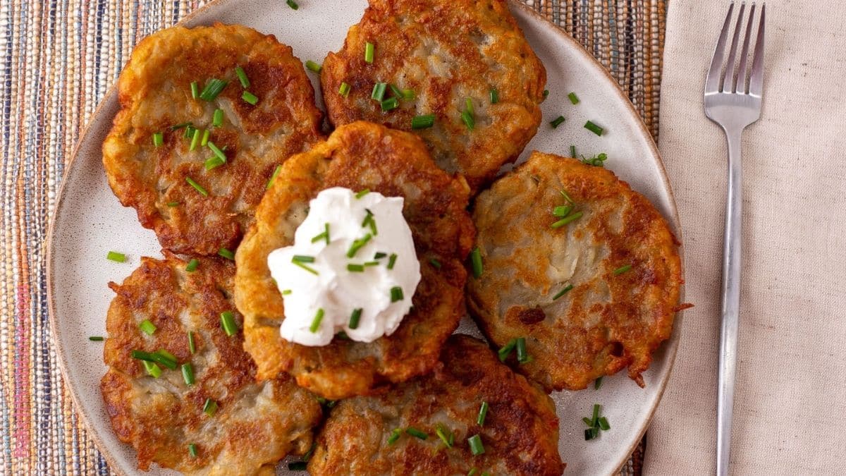 Wide image showing a stack of boxty Irish pancakes topped with sour cream and green onions.