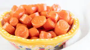 Wide image of a bowl of candied carrots.