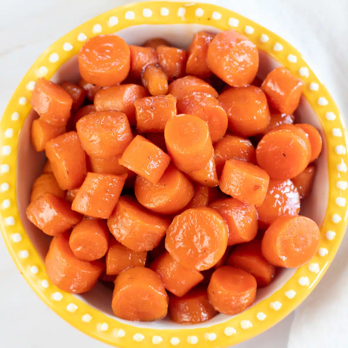 Square image of a bowl of candied carrots.