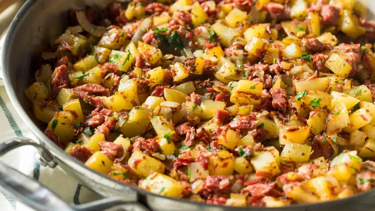 Wide image of corned beef hash in a pan.