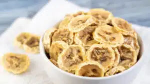Wide image showing a bowl full of dehydrated banana chips.