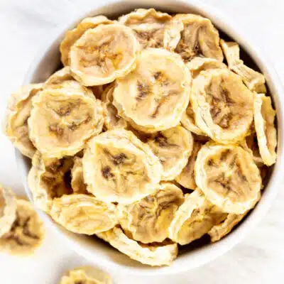 Square overhead image showing a bowl full of dehydrated banana chips.