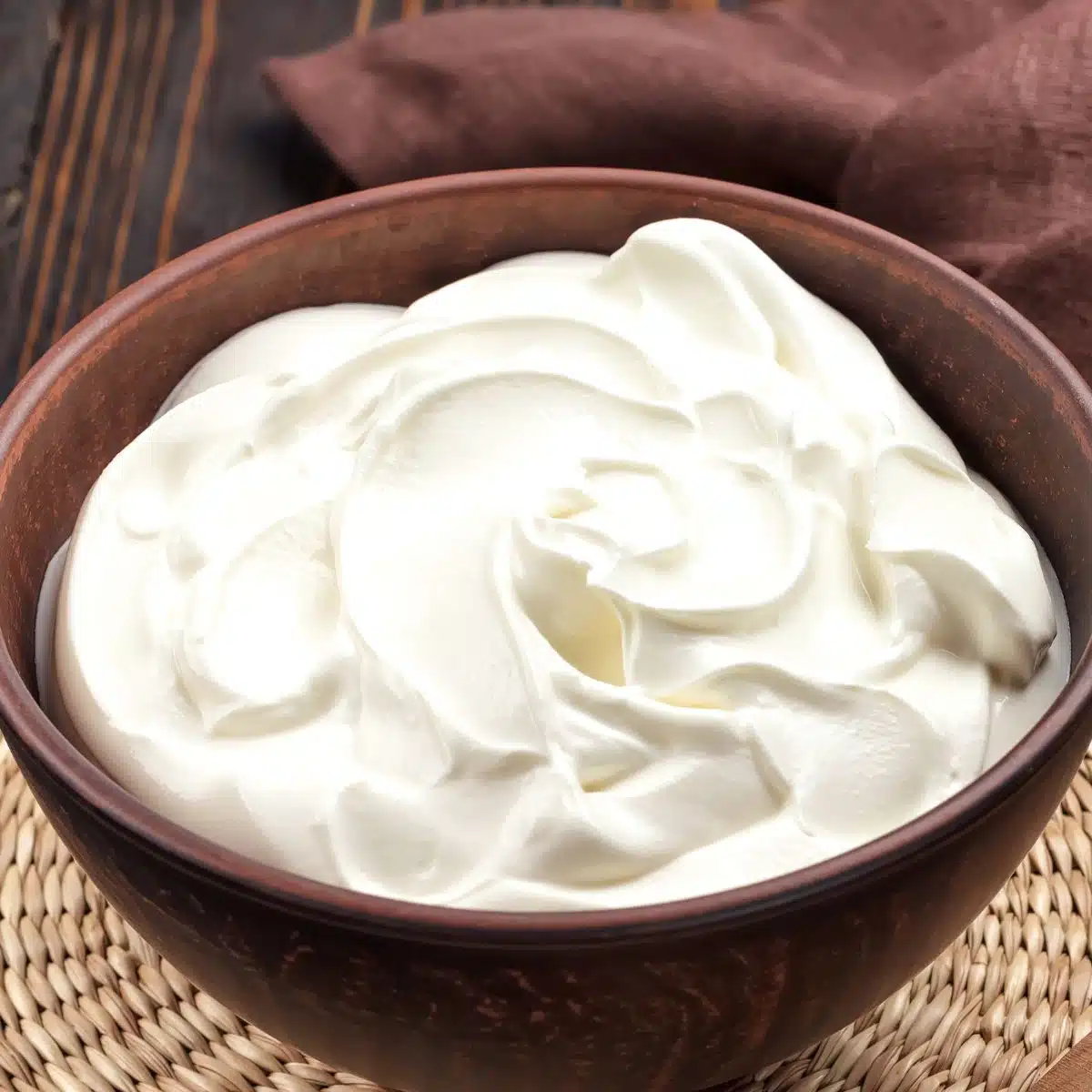 Square image showing sour cream in a wood bowl.