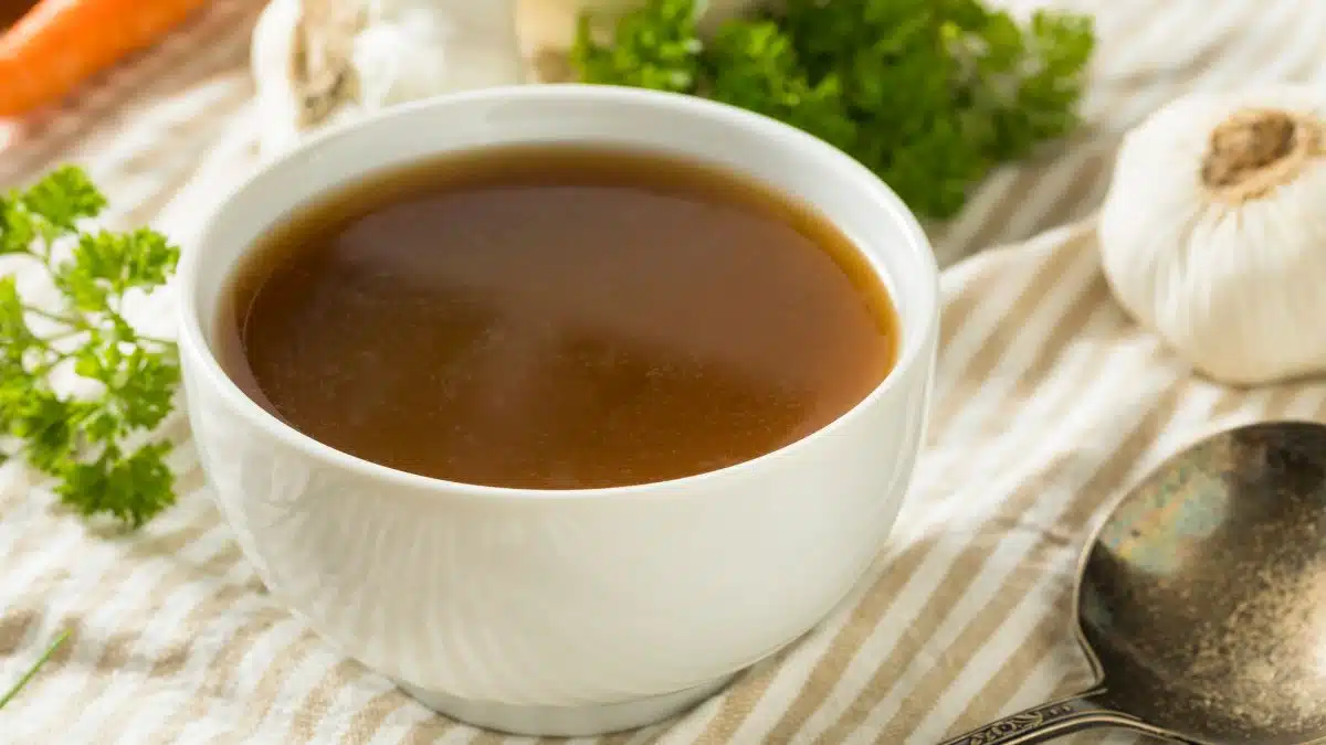 Wide image of bone broth in a small white bowl.