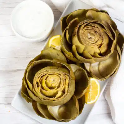 Square overhead image of instant pot artichokes on a white plate.