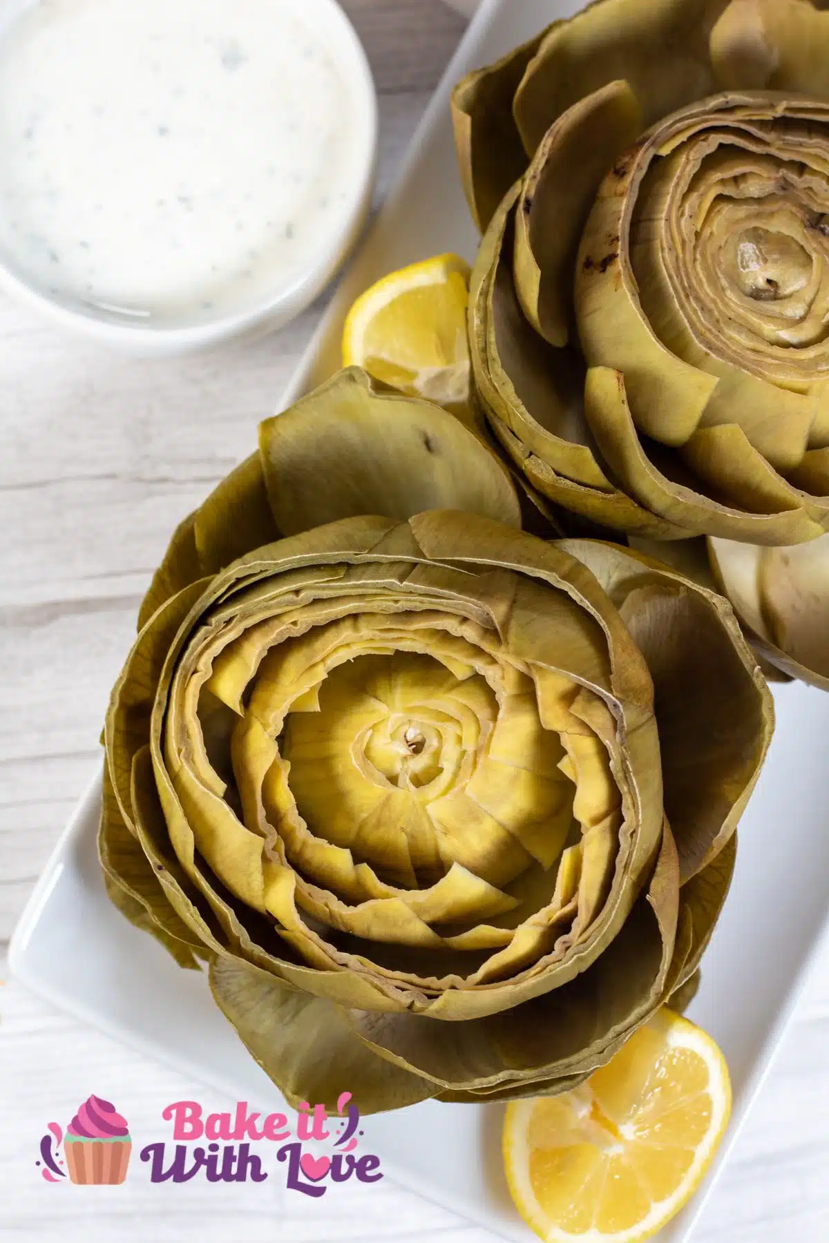 Tall image of instant pot artichokes on a white plate.