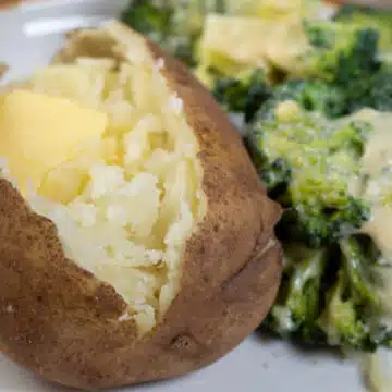 Wide image showing a plate with a instant pot baked potato and broccoli on the side.