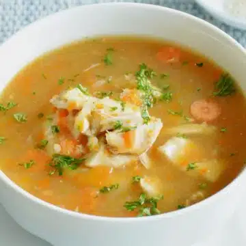 Wide image showing a white bowl of instant pot chicken soup.