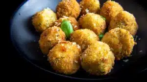 Square image of risotto balls aka arancini on a plate.