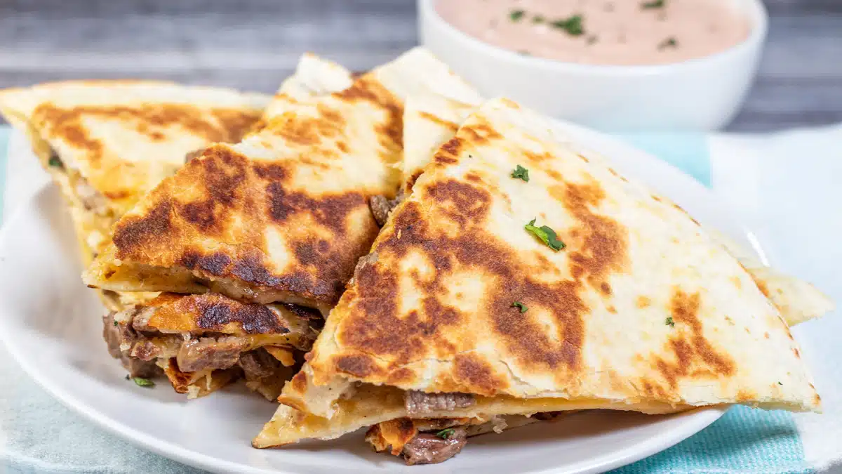 Wide image of sliced and stacked steak quesadillas.