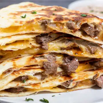 Wide close up image of sliced and stacked steak quesadillas.