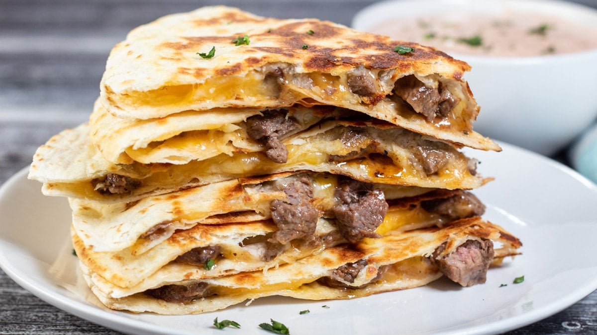 Wide close-up image of sliced and stacked steak quesadillas.