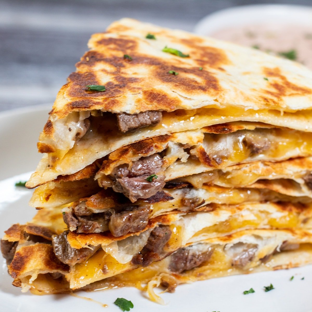 Square image of sliced and stacked steak quesadillas.