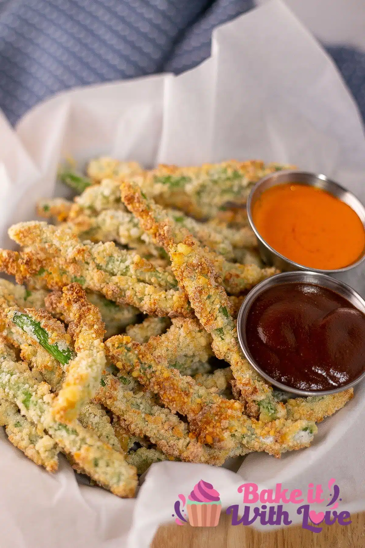 Tall image of a basket of air fried green bean fries with dipping sauces.