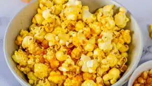 Tasty cheddar popcorn shown closeup from overhead in a white bowl for serving.