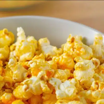 Best cheddar popcorn recipe pin with popcorn served in a bowl for snacking and text title overlay.