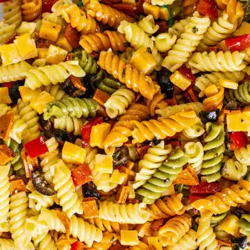 Tall image of pasta salad with Italian dressing in a white bowl.