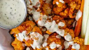 Wide overhead closeup of the roasted buffalo cauliflower with ranch dressing drizzled over the basket of food.
