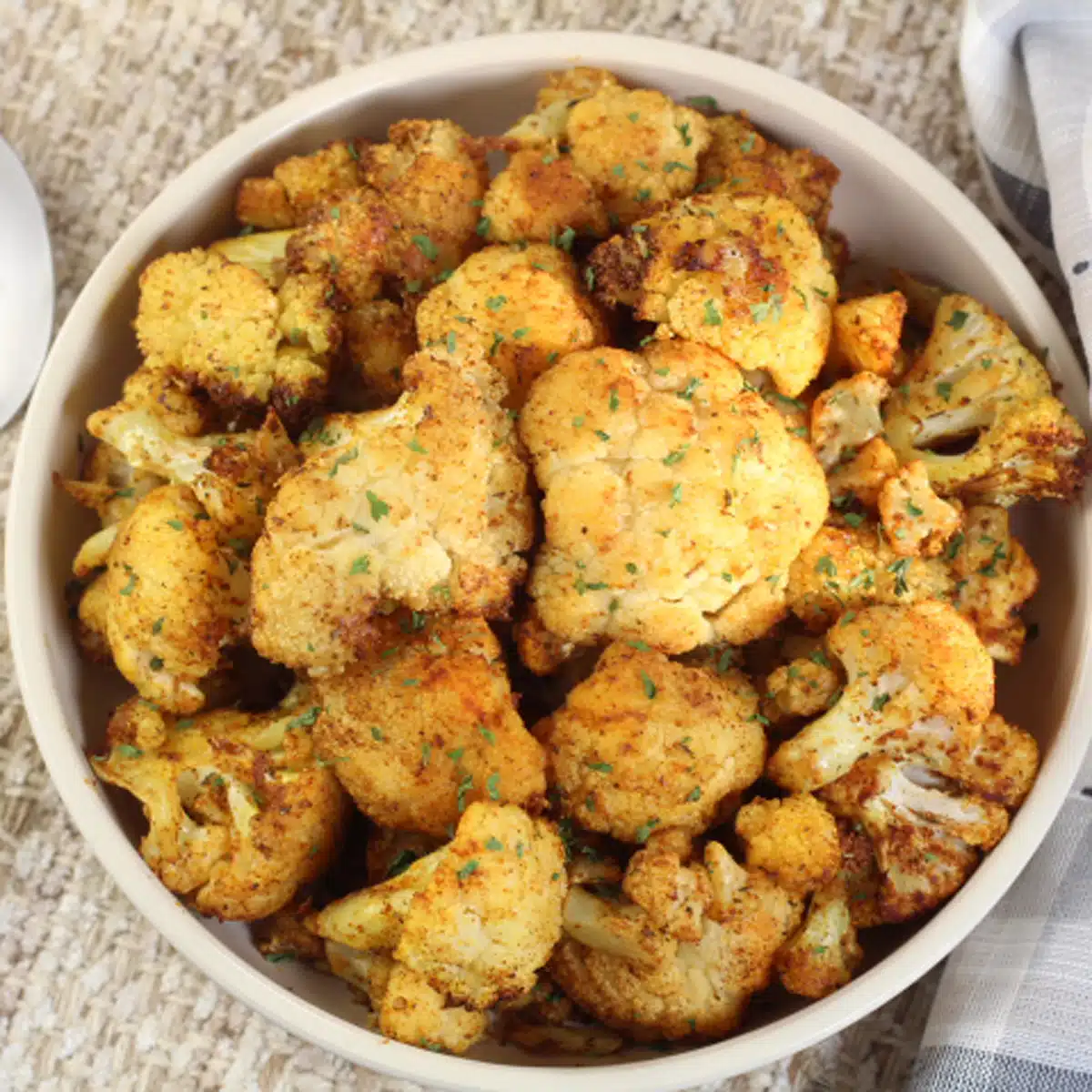 Square image showing a bowl of air fryer cauliflower.
