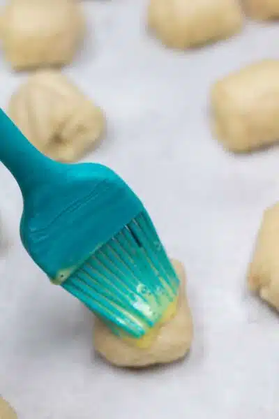 Process image 8 showing brushing egg wash on dough rolls.