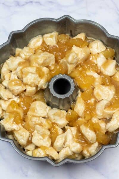 Изображение на процеса 9, показващо комбинирани нарязани бисквити в тава с добавена смес за ябълков пай.