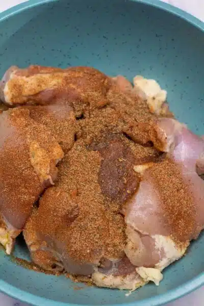 Process image 1 showing boneless chicken thighs and seasoning in a bowl.