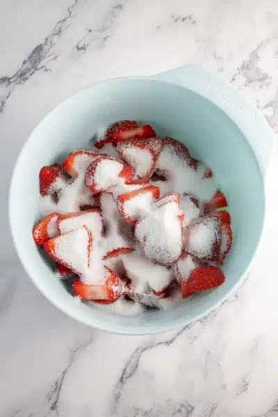 Process image 1 showing sliced strawberries in a mixing bowl with sugar.