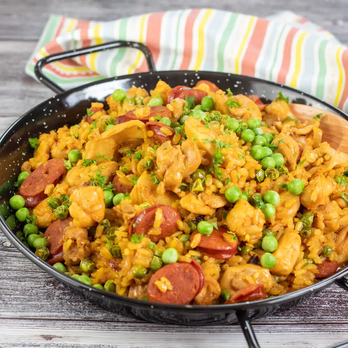 Vierkante afbeelding van kip chorizo ​​paella in een paella pan.