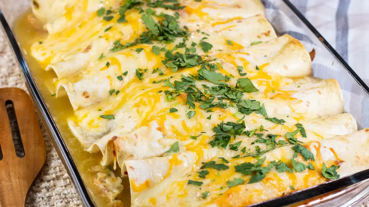 Wide image of chicken enchiladas with green sauce.