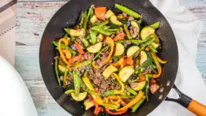 Wide image showing ground beef stir fry in a wok.
