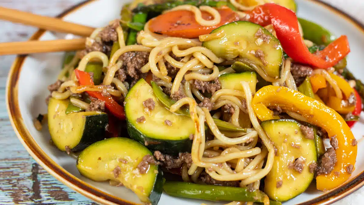 Wide image showing ground beef stir fry with noodles.