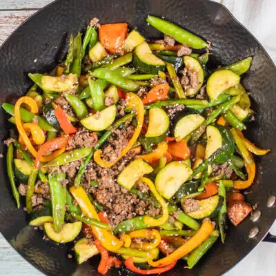 Square image showing ground beef stir fry in a wok.