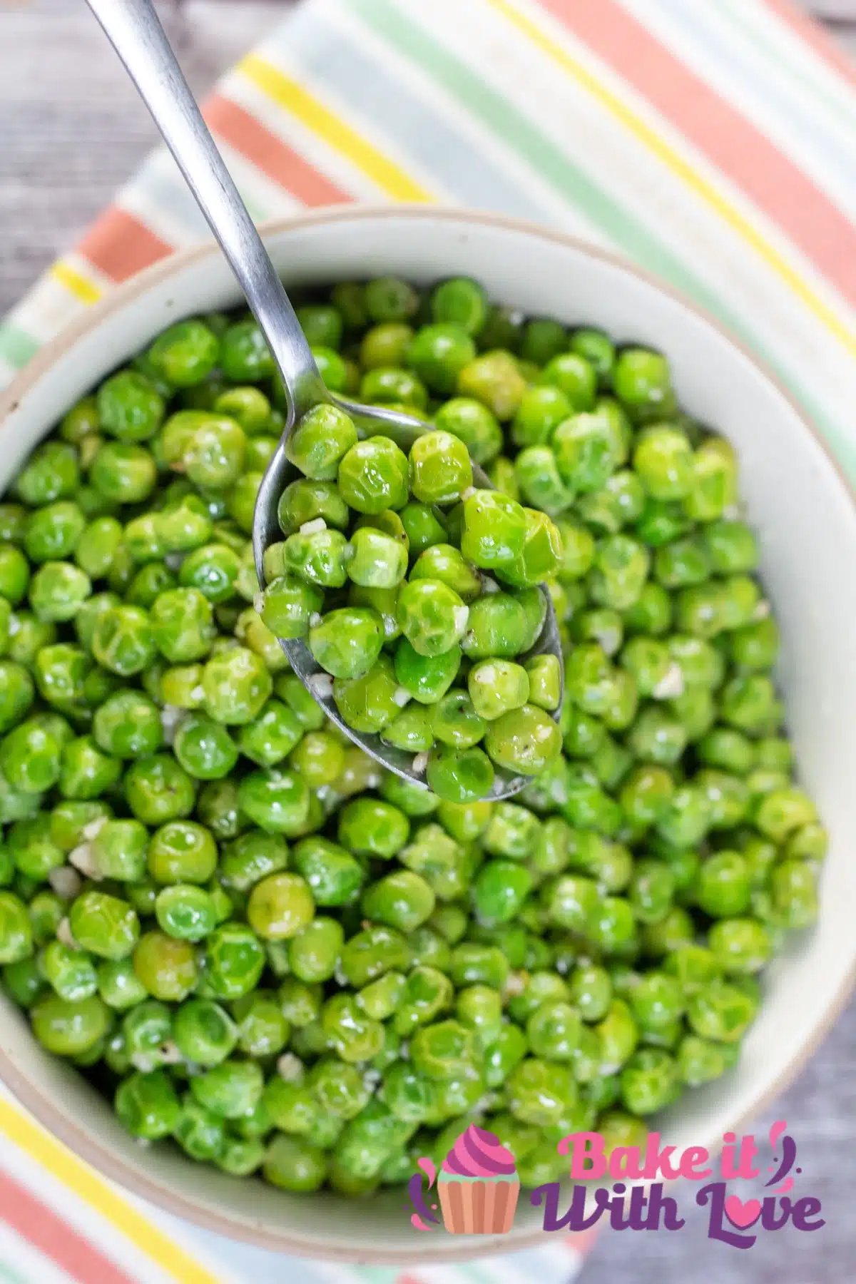 Tall image of a bowl of green peas, cooked from frozen.