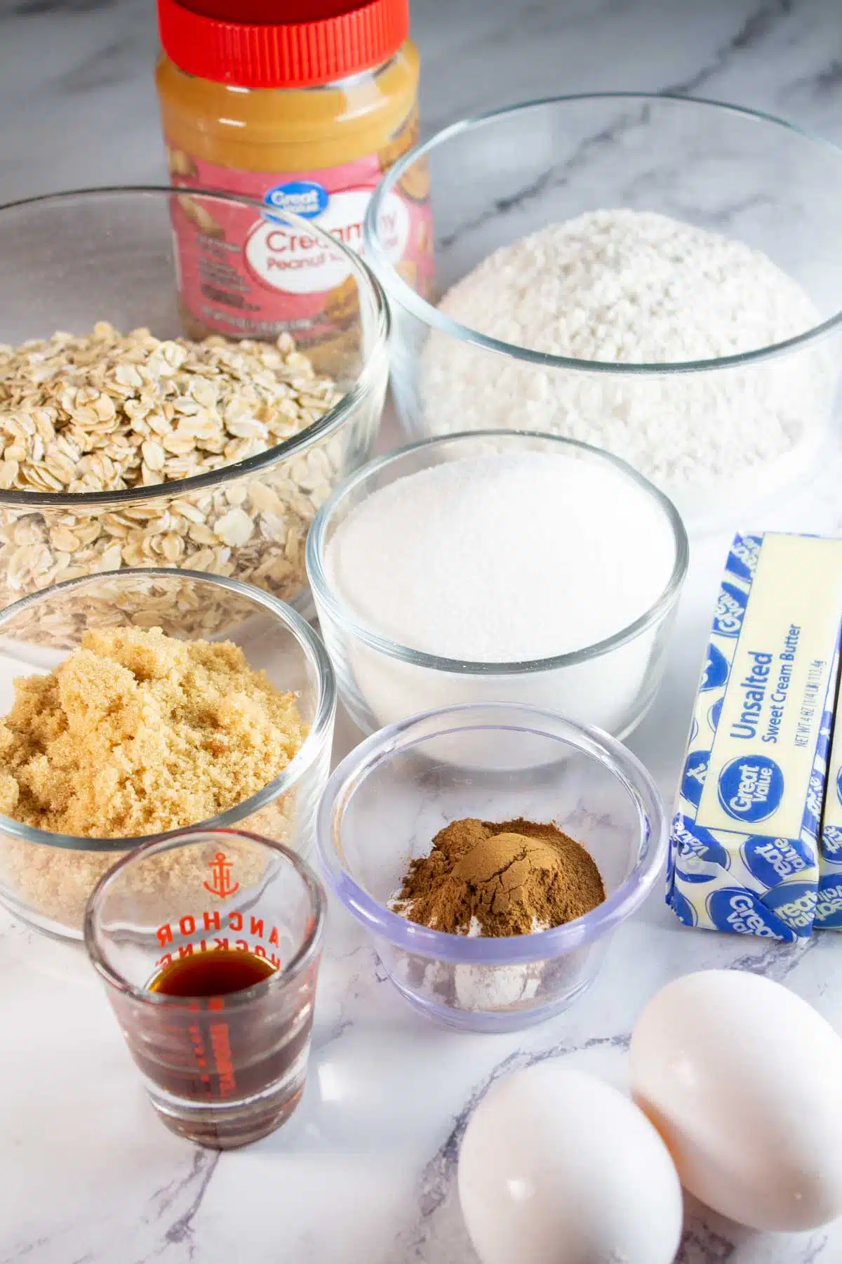 Tall image of ingredients needed for oatmeal peanut butter cookies.
