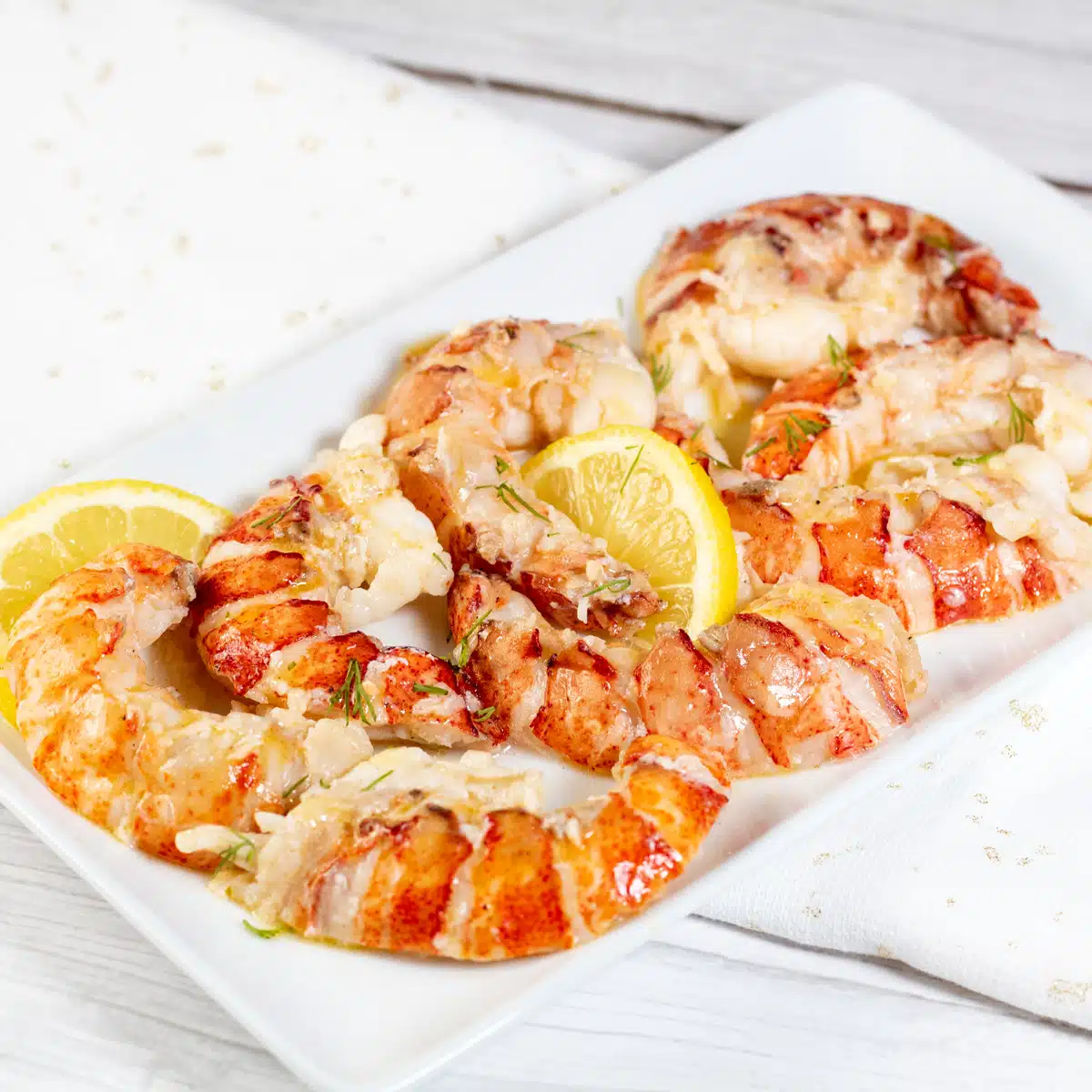 Square image showing butter poached lobster tails.