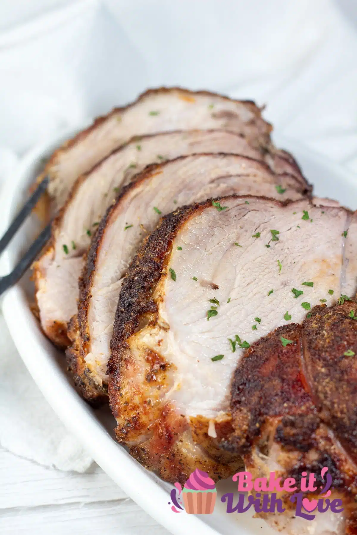 Tall image of sliced pork picnic roast on a white serving platter.