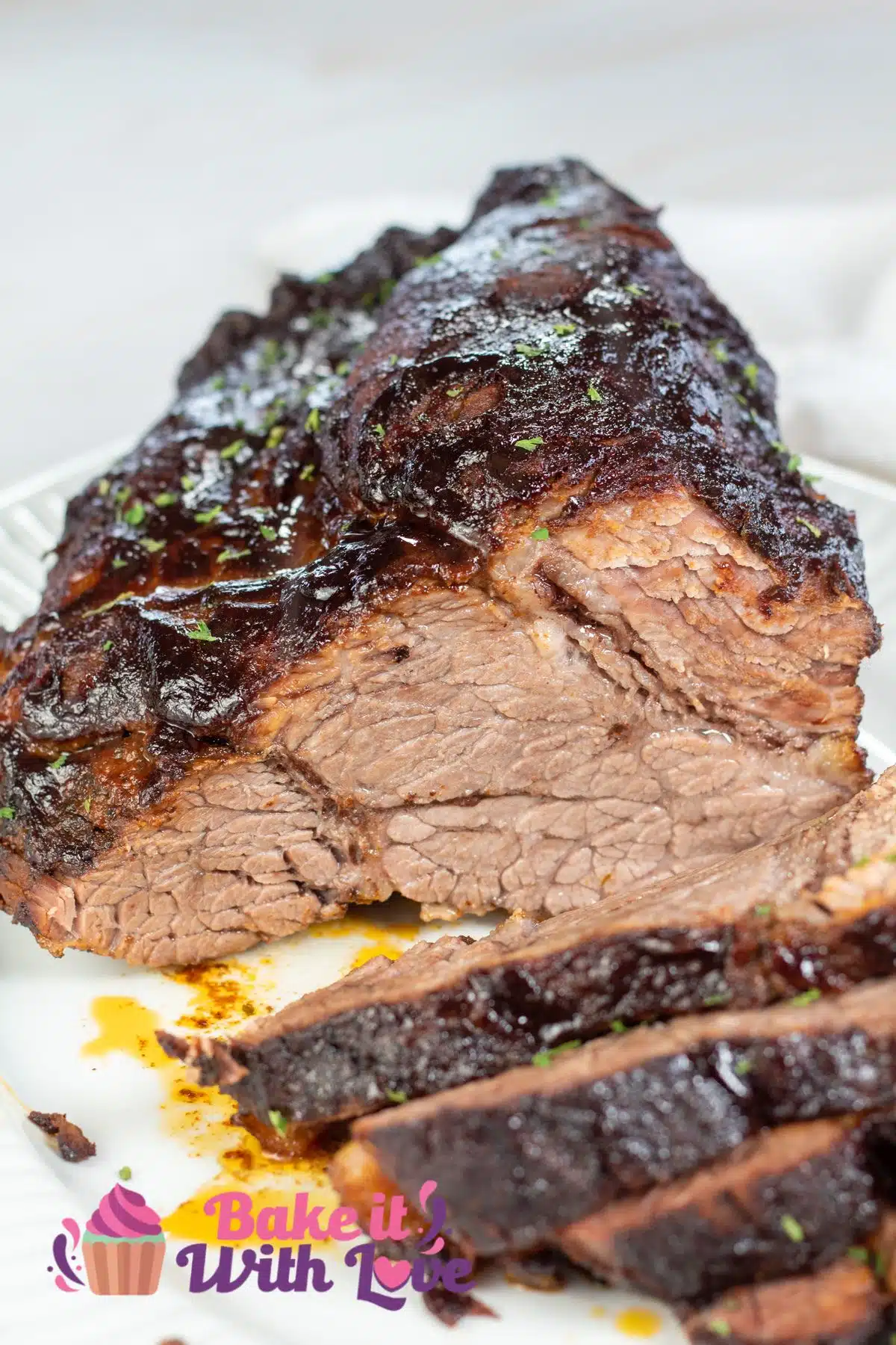 Tall image of slow cooker brisket, sliced and on a white serving dish.